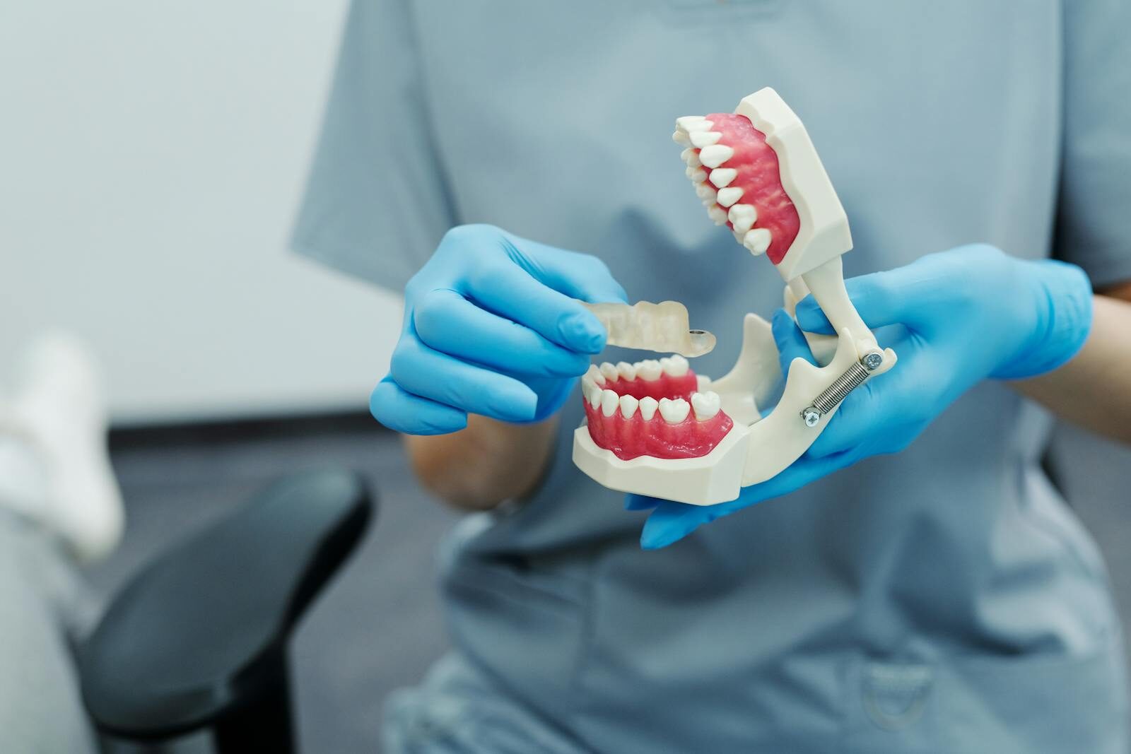 Photo by Diana Polekhina Close-up of a dental professional demonstrating with a teeth model in a clinic setting.